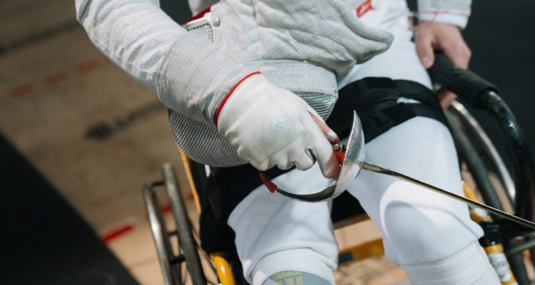 Close-up of a wheelchair fencer gripping a sabre, showcasing focus and determination in sport